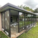Glass sunroom addition with black aluminum frame under construction near Orlando
